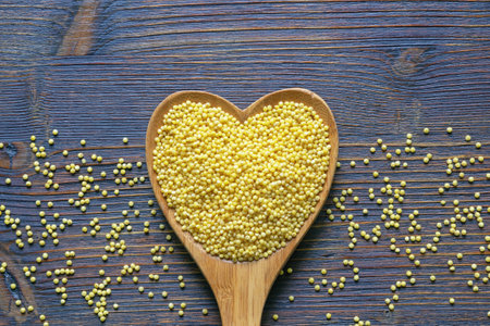 Millet groats in heart shaped spoon on rustic table. Flat lay, copy spaceの写真素材