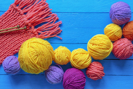 Hobby and knitting concepts. Colorful balls of wool, knitted scarf and knitting needles on blue rustic table. Flat lay, copy spaceの写真素材
