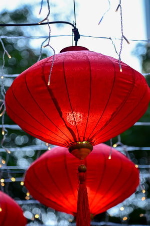 Close-up of the traditional Chinese red lantern with outdoor starry solar string lights. Big red lantern. Festive decoration. Mid-autumn festival, Chinese New Year decoration for cの写真素材