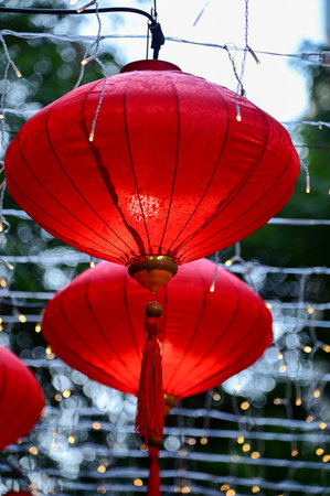 Close-up of the traditional Chinese red lantern with outdoor starry solar string lights. Big red lantern. Festive decoration. Mid-autumn festival, Chinese New Year decoration for cの写真素材