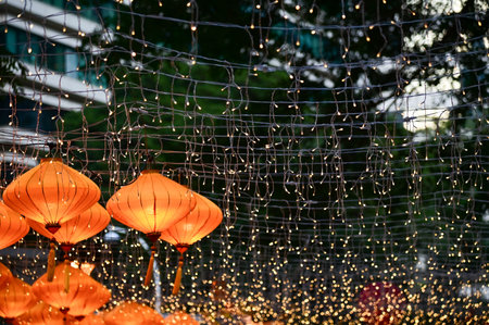 Close-up of the traditional Chinese lantern with outdoor starry solar string lights. Orange lantern. Festive decoration. Mid-autumn festival, Chinese New Year decoration for celebrの写真素材
