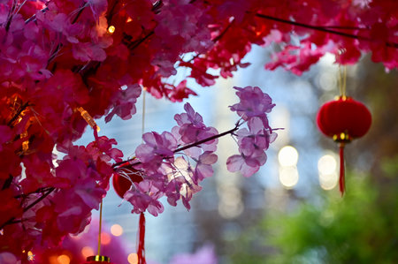 Close-up of the artificial peach blossom flower with the Chinese traditional red lantern decor in background. Festive decoration and celebration. Chinese New Year decoration.の写真素材