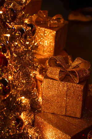 Close-up of the present boxes under the Christmas trees with colorful ornaments. Christmas presents,...