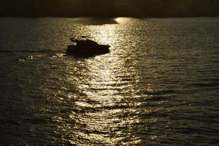 The seascape at sunset with ships and cityscape in the background. Sun-rays reflected on the calm sea. Sea background and cityscape. Nature concept.の写真素材