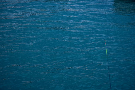 Sea with a fishing rod. Calm seascape, wave pattern. Hobby and nature scene.の写真素材
