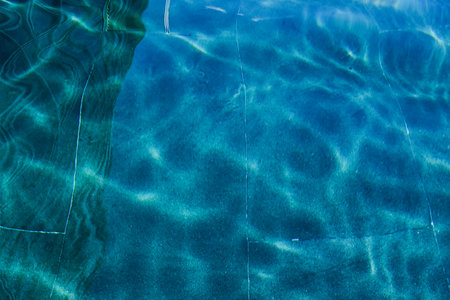 Close-up of the water of a swimming pool with the sunlight reflection. The scene of the swimming...