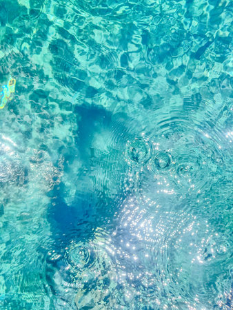 Close-up of the water of a swimming pool with the sunlight reflection. The scene of the swimming pool in the sunny day. Relaxation and holiday concept.の写真素材