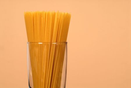 Spaghetti in clear glass with wheat colored backgroundの写真素材