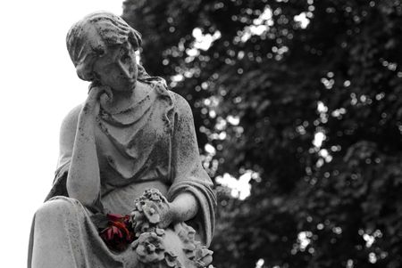 Black and White Granite statue of woman holding a colored red rose at gravesiteの写真素材
