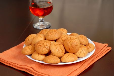 A plate of crisp Amaretti cookies resting on an orange napkin with a snifter of Amaretto in backgroundの写真素材