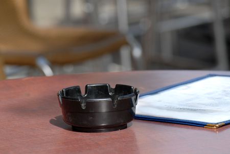 An ashtray and menu on a table in a sidewalk cafe dining areaの写真素材