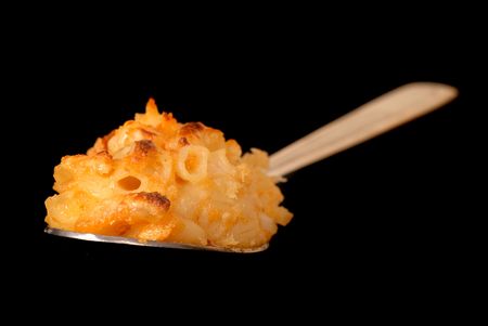 A spoonful of macaroni and cheese on black background with shallow depth of field