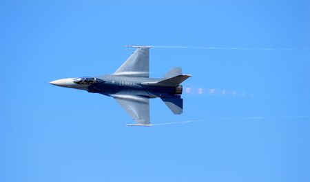 A Navy F-14 reaching supersonic speed against a pure blue sky
