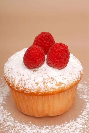 Freshly baked vanilla cupcake with raspberries and powdered sugarの写真素材