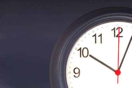 Closeup of a clock agains a blue wall showing time ticking awayの写真素材