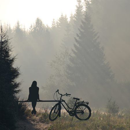 Woman with bicycle  resting on a benchの写真素材
