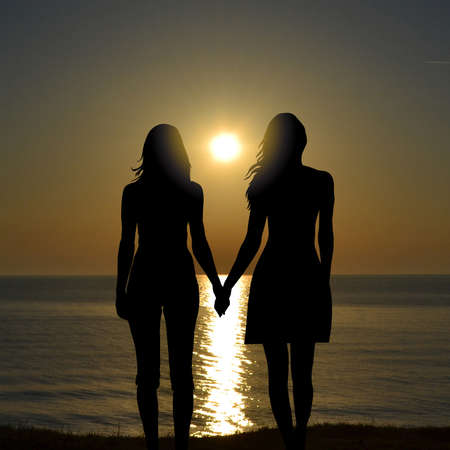Back view of two women on holiday travel vacation beach watching sunriseの写真素材