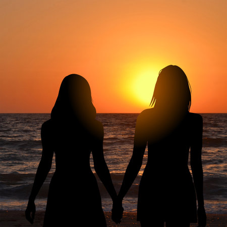 Lesbian couple admiring the sunrise at the seasideの写真素材