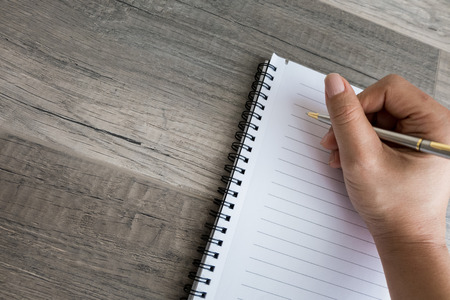 A hand writing in a blank noteの写真素材