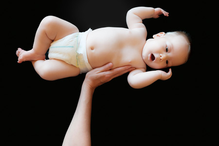 innocent baby lifted in a black backgroundの写真素材
