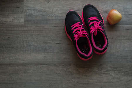 Pink sport shoes with apple on wooden backgroundの写真素材