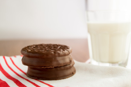 Chocolate cookies on white linen napkin and a glass of milk on wooden, selective focusの写真素材