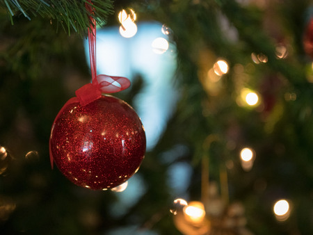 Closeup of red and silver ball hanging from a decorated Christmas treeの写真素材