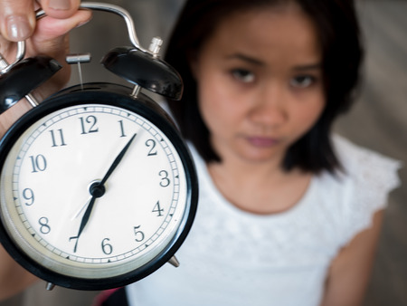 Woman holding a clock with serious face , dateline concept