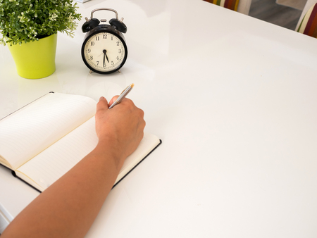 Hand writing on a notebook on  a white tableの写真素材