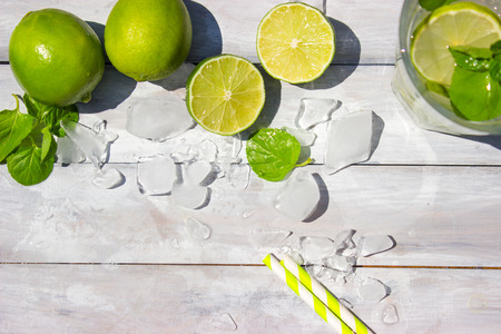 Mojito and limes on the white wooden background
