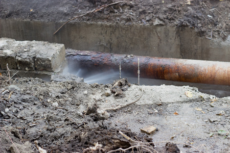 Broken old pipes of the heating system; water splashing under pressureの写真素材
