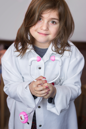 Beautiful little girl holds a toy stethoscope and playing a doctorの写真素材