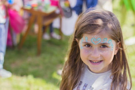 Outdoor portrait of a beautiful little girl with painted face
