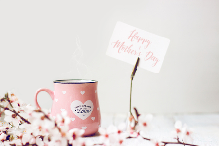 Pink coffee mug, white cherry flowers and ''Happy Mother's Day'' note, on white backgroundの写真素材