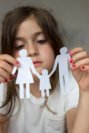 Little girl holds paper chain family; broken family or divorce conceptの写真素材
