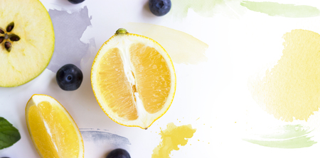 Lemon, apple and blueberries on white background with watercolor strokes; creative layout with copy spaceの写真素材