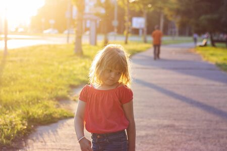 Little girl making faces and having fun on beautiful summer sunsetの写真素材