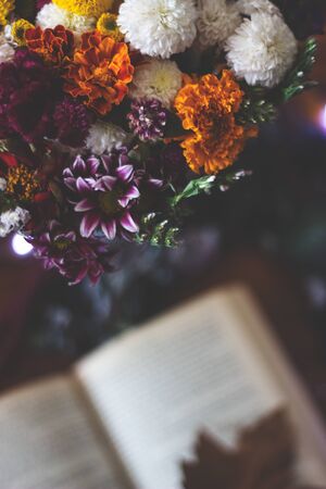 Top view of a bouquet of flowers and open book on the tableの写真素材