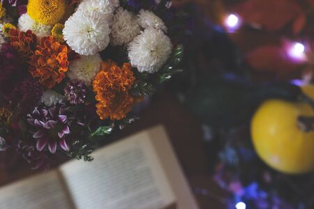 Top view of a bouquet of flowers and open book on the tableの写真素材