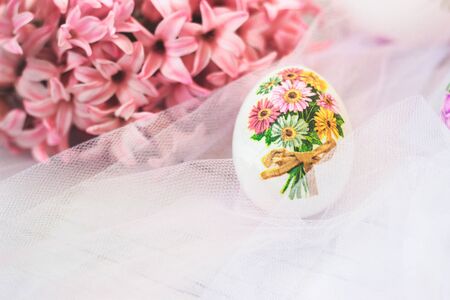 Decoupage decorated Easter egg, with pink hyacinths flowers, on white tulle backgroundの写真素材
