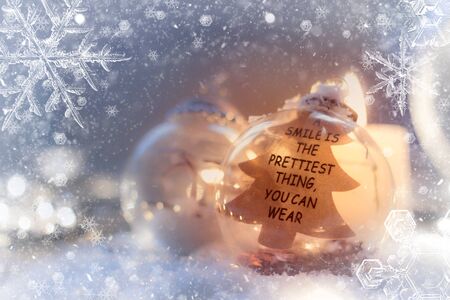 Christmas background - glass ornament with text "a smile is the prettiest thing you can wear", with snowflakes and glitterの写真素材