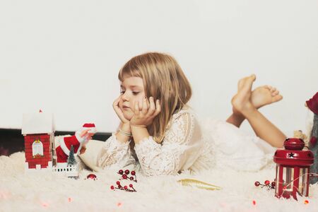 Little girl laying on the floor, playing with Christmas decoration; Christmas background with copy spaceの写真素材