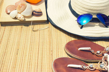 Beach accessories-sunglasses, flip flops, book and the hatの写真素材