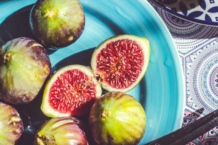 Whole and half cut ripe figs on blue plate; fruit backgroundの写真素材