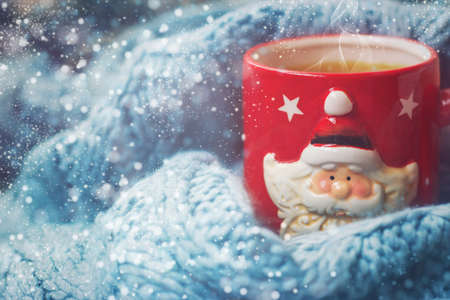Winter background - red cup with santa claus and woolen scarf
