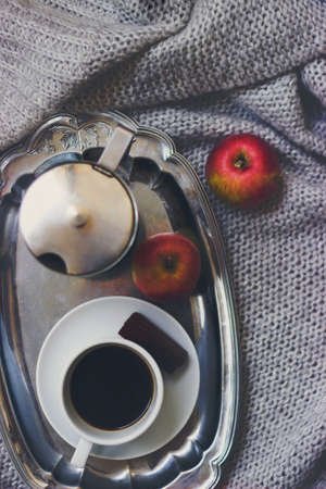 Cup of coffee, moka pot on silver tray and apples on the grey knitted blanket, top view, winter cozy backgroundの写真素材