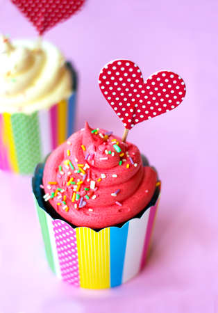 Tasty strawberry cupcake with red heart topper pink background. Valentine background