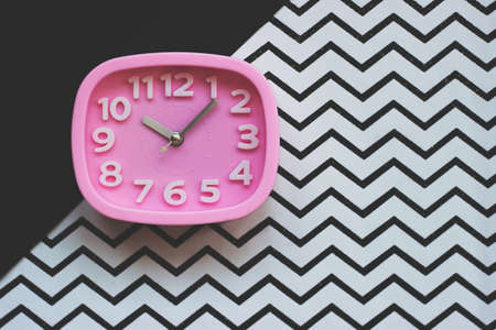 Pink alarm clock on black and chevron  background