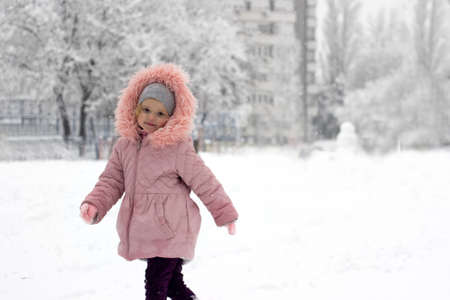 Little girl is sitting in the snow, making fun outside, on fresh snow that fell over night; with copy spaceの写真素材