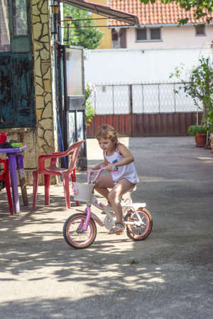 Little girl is driving her bicycle in the backyardの写真素材